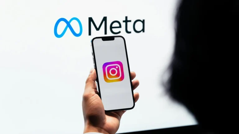 cellulare con logo instagram e con dietro uno schermo con logo meta